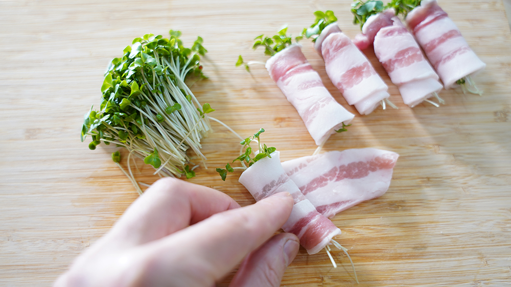 ブロッコリースプラウトを豚バラ肉で巻いている様子