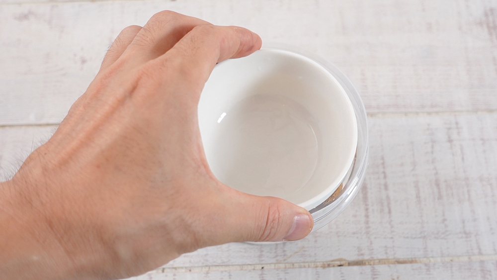 パキラの種が入った容器に重しのお皿を乗せている様子